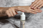 Hand applying clear serum from Gillette Venus Daily Soothing Serum pump bottle onto smooth towel-dried skin in soft studio lighting
