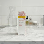 Burt's Bees Hydrating Day Lotion box on bathroom marble vanity alongside clear glass carafe of water and organized acrylic skincare tray
