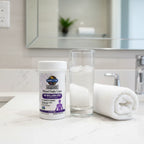 Garden of Life Mood Daily Care Probiotics bottle on white quartz bathroom vanity with rolled cotton towel and glass of water