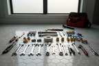 Professional plumber toolkit on clean bathroom tile floor with thread-seal tape