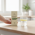 Woman holding Nature's Best Lymphatic Drainage Liquid Herbal Extract 2 fl oz box over a wood kitchen table next to lemon water
