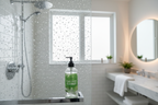 Pristine glass shower door with sparkling water droplets and a plant-based cleaning spray bottle on the ledge