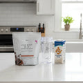 Plexus Lean Whey Milk Chocolate shake bag on white quartz kitchen island with clear blender bottle and almond milk carton