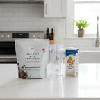 Plexus Lean Whey Milk Chocolate shake bag on white quartz kitchen island with clear blender bottle and almond milk carton