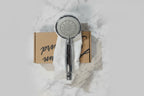 Professional flat-lay of American Standard polished chrome handheld shower head on white marble surface