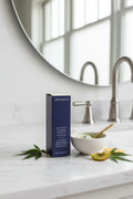 Clean minimalist bathroom counter featuring a deep navy blue premium skincare facial treatment box on white marble