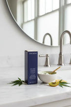 Clean minimalist bathroom counter featuring a deep navy blue premium skincare facial treatment box on white marble