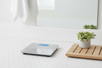 Taylor Digital Bath Scale on white bathroom floor beside wooden bath mat and small succulent
