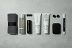 Minimalist toiletry kit flat lay on neutral stone surface featuring travel-sized skincare tubes
