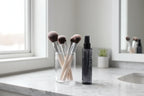Clean vanity setup with makeup brushes and professional brush cleaning spray bottle on marble surface
