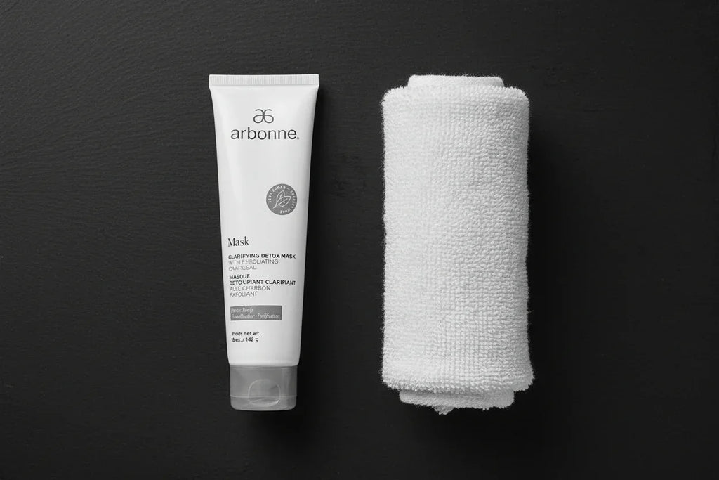 Arbonne Clarifying Detox Mask white tube flat lay on slate surface with rolled white towel