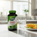 Nature's Way Vitamin C 1000mg bottle on quartz breakfast bar with fresh glass of water and plate of sliced oranges