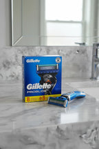 Gillette ProGlide 8 Count Razor Blade Refills displayed on modern bathroom countertop with razor handle morning light