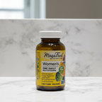 MegaFood Women's One Daily multivitamin amber glass bottle in soft natural window light on white quartz countertop – More4less Outlet