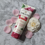 Fresh pink rose petals and camellia flower beside a white skincare tube on clean marble surface
