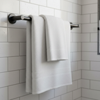 White bath towel draped over sleek matte black towel bar on white subway tile bathroom wall