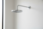 Grohe Classic II polished chrome shower arm with dome flange installed in minimalist white bathroom with matching chrome shower head and morning light