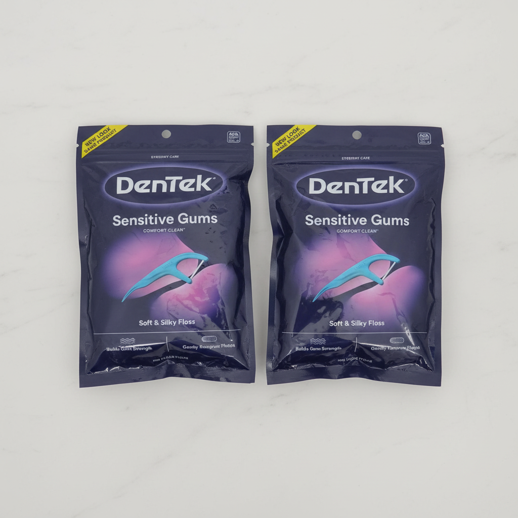 Two sealed DenTek Sensitive Gums Comfort Clean floss pick bags on a light surface