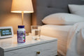 Natrol Melatonin 5mg on nightstand with water glass and alarm clock bedtime lifestyle