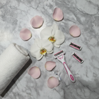 Spa-inspired flat lay with white orchid flowers and pink petals on marble surface