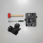 Flat-lay of automotive suspension repair tools including torque wrench socket set rubber mallet and mechanic's gloves on clean garage floor
