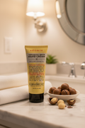 Adamia hand cream tube on marble vanity with macadamia nuts and white towel