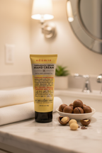 Adamia hand cream tube on marble vanity with macadamia nuts and white towel