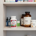 Doctors' Preferred Omega Q Plus bottle in organized family health cabinet with white wood shelving and clinical supplement jars