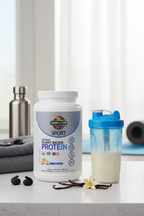 Garden of Life Sport Organic Plant Protein vanilla tub on gym counter with shaker bottle and vanilla beans