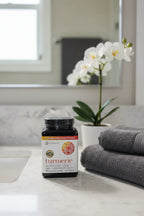 Youtheory Turmeric Extra Strength on bathroom quartz vanity next to white orchid and charcoal hand towels morning regimen