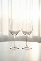 Minimalist modern lifestyle shot of Riedel crystal wine glasses catching warm afternoon light highlights with bokeh background