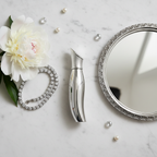 Lifestyle — elegant silver perfume bottle on white marble vanity beside diamond bracelet, white peony blooms, and silver mirror — editorial for visual context only