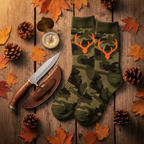 Two pairs of Realtree green camo crew socks with hunting gear flat lay on weathered wood — More4less Outlet