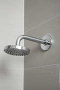 Grohe Classic II polished chrome shower arm with dome flange installed on grey textured tile shower wall with water droplets on chrome surface