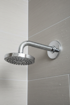 Grohe Classic II polished chrome shower arm with dome flange installed on grey textured tile shower wall with water droplets on chrome surface