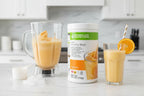 Bright studio setting showing refreshing orange cream shake being prepared with Herbalife Formula 1 canister
