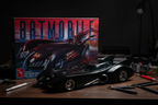 AMT 1/25 scale Batman and Robin Batmobile model kit fully assembled on dark wood hobby desk with model building tools and dramatic moody lighting