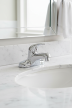 American Standard Colony Soft polished chrome single control lavatory faucet installed on white marble bathroom vanity in morning light