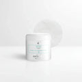 Clean minimal white bathroom counter featuring a white skincare jar with teal label accents