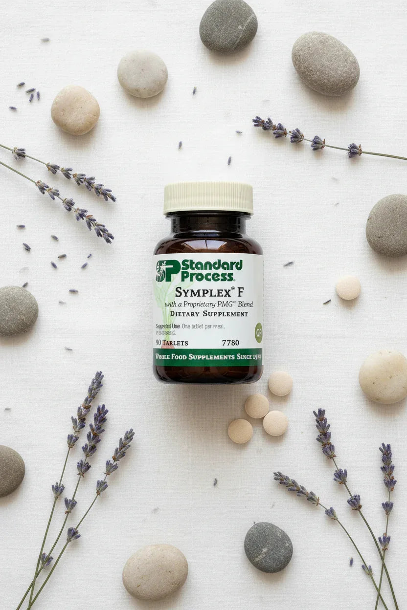 Standard Process Symplex F supplement bottle flat lay on white linen with lavender sprigs botanicals and smooth stones