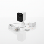 Flat lay of Blink Mini 2 white security camera with USB-C cable power adapter and mounting screws on white surface