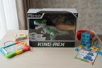 Vivitar Robo King-Rex motorized dinosaur toy on wooden desk near electronic accessories