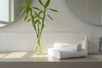 Minimalist bathroom counter with fresh green bamboo stems white towels and clean morning lighting