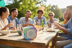 Bytech Mini Karaoke Speaker with rainbow LED ring on a patio table at a sunny outdoor summer gathering