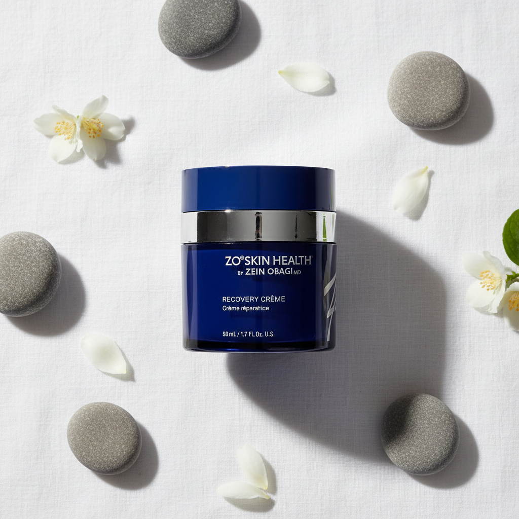 ZO Skin Health Recovery Crème navy blue jar flat lay on white linen with river stones and jasmine petals