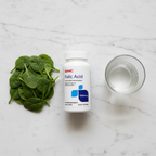 GNC Folic Acid 1000mcg bottle on marble with fresh spinach leaves and glass of water – More4less Outlet