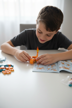 Child building MEGA Pokémon Charizard from orange and teal bricks on white table with instruction booklet open nearby