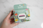Hand holding Gillette Venus Comfortglide Sugarberry Rifle Paper Co. limited edition box with botanical floral design against white marble tile
