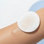 Cotton pad with clear liquid exfoliant being swept across smooth skin close-up lifestyle photo