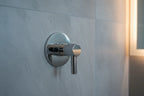 Luxury spa bathroom detail of polished chrome shower volume control handle on stone tile